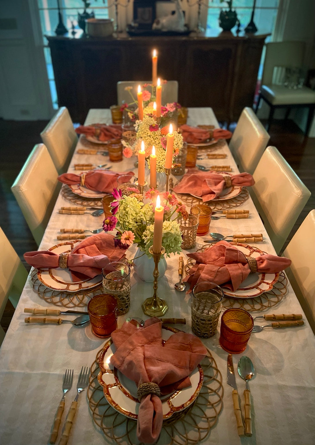 Table Terrain fall tablescape with coral linen napkins, amber glassware, bamboo flatware, flowers and candlelight